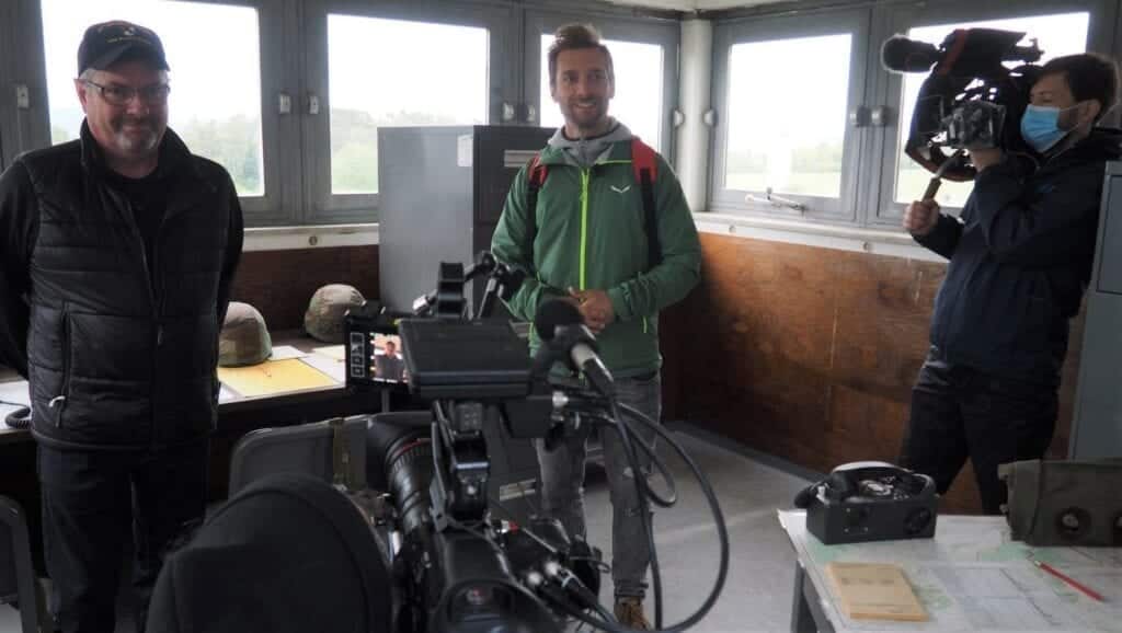 Auf dem Beobachtungsturm im US-Camp im Fokus der Kamera: US-Veteran Vern Croley (links) aus Rasdorf beantwortet die Fragen von Moderator Daniel Aßmann (Mitte) für das WDR-Reisemagazin „Wunderschön“.
