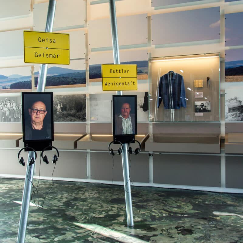 In der Dauerausstellung im Haus auf der Grenze stehen neben den Ortsschildern Monitore mit Kopfhörern. In Videos erzählen Zeitzeugen aus der Region ihre persönlichen Geschichten.