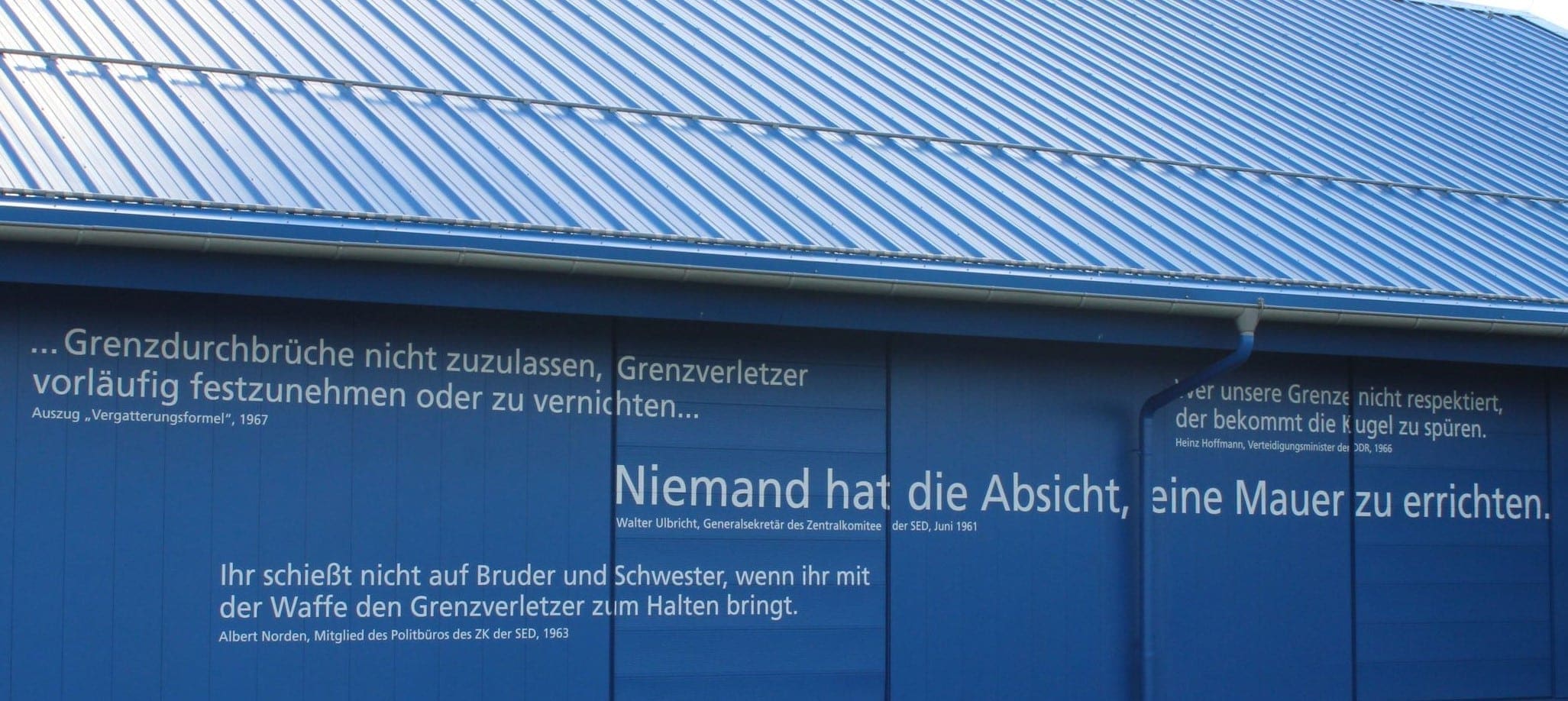 „Niemand hat die Absicht…“: Zitate und Aussagen, die im Zusammenhang mit der Innerdeutschen Grenze stehen, prangern als Mahnung an der Außenfassade am Haus auf der Grenze.
