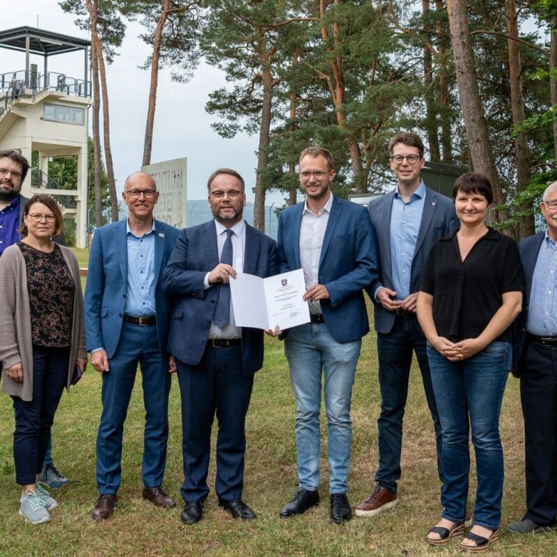 Die Gedenkstätte Point Alpha ist das Museum des Monats in Hessen. Bei der Preisübergabe im US Camp mit dem Beobachtungsturm im Hintergrund (von rechts): Carina Rothmann, Berthold Jost (beide Förderverein Point Alpha), Aline Gros (Point Alpha Stiftung), Sebastian Müller (Fuldaer CDU-Landtagsabgeordneter), Benedikt Stock (Geschäftsführender Vorstand Point Alpha Stiftung), Minister Timon Gremmels, Jürgen Hahn (Bürgermeister Rasdorf), Birgit Konrad, Jan Ludwig Antoni und Susanne Bott (alle Point Alpha Stiftung).
